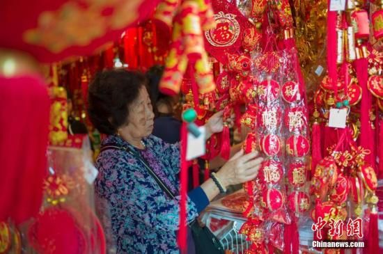 1月28日，正值中国民间传统的“小年”，海南海口大街小巷的“年味”渐浓。海口博爱路是当地有名的年货一条街，各种对联、中国结、红包、红灯笼等吸引了众多市民及游客前来置办年货，迎接猪年新春的到来。图为市民选购年货。<a target='_blank' href='http://www.chinanews.com/'>中新社</a>记者 骆云飞 摄